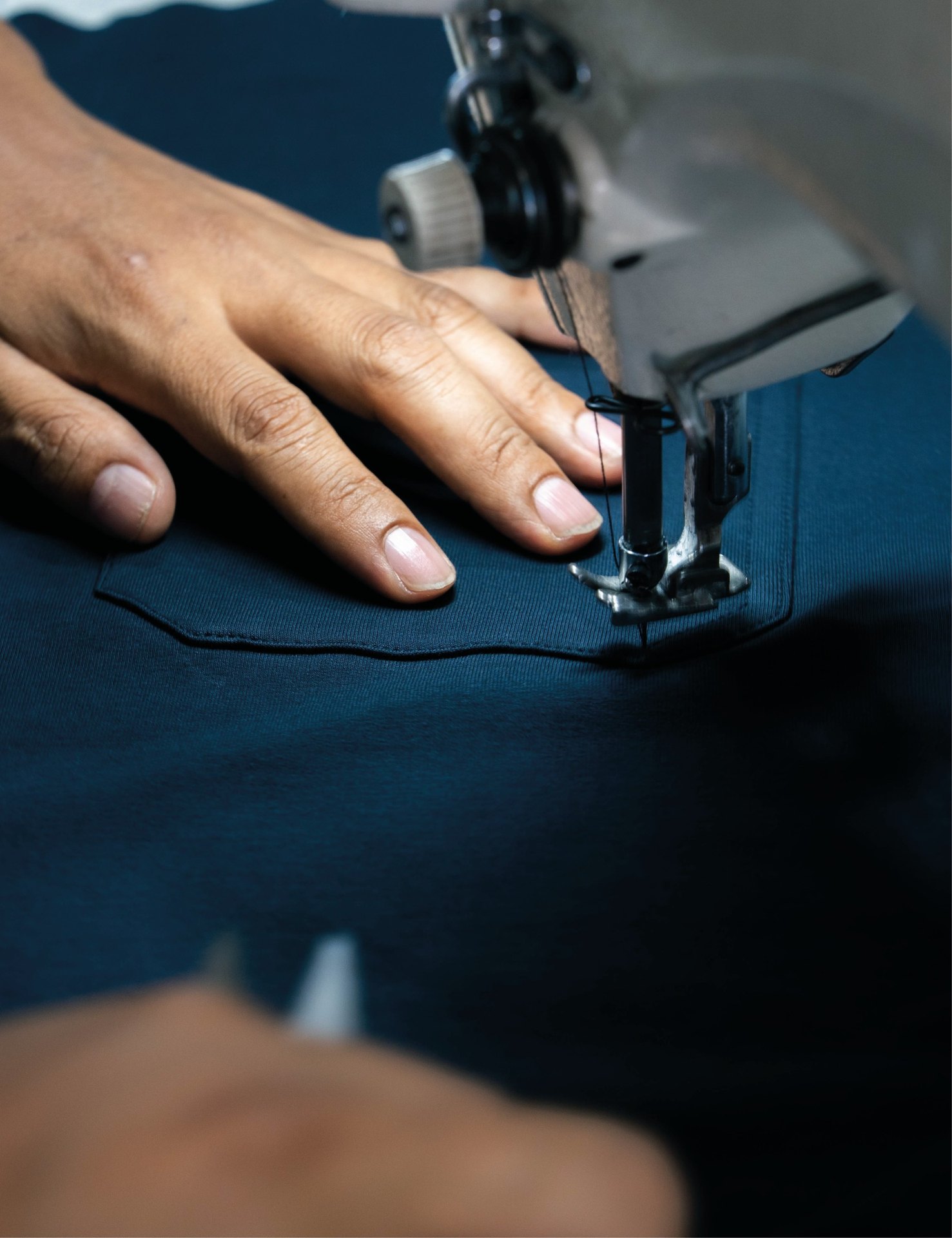 Sewing machine needle stitching navy fabric at Prospera